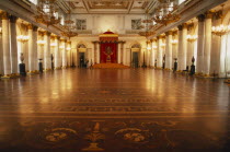 Winter Palace of the Hermitage  Hall of St. George.  Interior lined with columns and gold candelabra with lights reflected on polished floor surface.