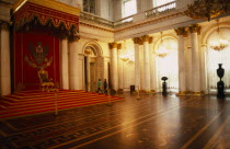 Winter Palace of the Hermitage  Hall of St. George.  Interior with throne on red dais with decorated canopy  lined by supporting columns and lights reflected in floor surface.