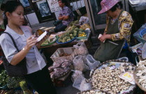 Wholesale Food Market.  Female buyer for restaurant purchasing mushrooms from vendor.Asian Prathet Thai Raja Anachakra Thai Siam Southeast Asia Siamese