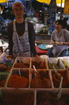 Wholesale Food Market.  Male vendor behind stall selling  selection of curry pastes displayed in plastic bowls. Asian Prathet Thai Raja Anachakra Thai Siam Southeast Asia Siamese