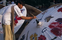 Tha Phae Road.  Young man taking part in umbrella painting competition on a sunday when the road is closed to traffic. Asian Prathet Thai Raja Anachakra Thai Siam Southeast Asia Immature Male Men Guy...