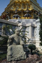 Aka Wat Phra Kaeo. Stone statue on rockery next to small tree in groundsPrathet Thai Raja Anachakra Thai Religion Siam Southeast Asia Asian Religious Siamese