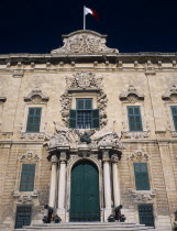 Auberge de Castille et Leon. Decorative baroque facade with steps leading to green doorway flanked by pillars and cannons with the Maltese flag flying from roof. Official residence of the Prime Minist...