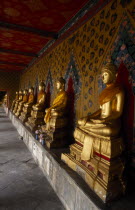 Wat Arun. Golden seated Buddha statues in cloister of Ordination Hall.