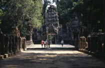 Preah Khan Processional Way leading to the causeway with tourists approaching the four faced East gate Asian Cambodian Kampuchea Religion Southeast Asia 4 History Holidaymakers Kamphuchea Religious T...