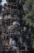 Neak Pean.  Tourists lighting incense at entrance to small temple on circular terrace.Asian Cambodian Kampuchea Religion Southeast Asia History Holidaymakers Kamphuchea Religious Tourism