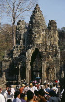 Crowds of visitors and traffic approaching South Gate or gopura with four huge heads each facing different directions. Asian Cambodian Kampuchea Southeast Asia 4 History Kamphuchea