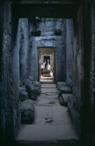 Preah Khan.  View through narrow passageway towards visitors beside Shiva plinth.Asian Cambodian Kampuchea Religion Southeast Asia History Holidaymakers Kamphuchea Religious Siva Tourism Tourist Sigh...