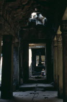 Preah Khan.  Elderly nun sitting beside stupa framed in series of doorways in colonnaded passageway.Asian Cambodian Kampuchea Religion Southeast Asia History Kamphuchea Old Senior Aged Religious