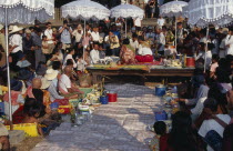 Shaman ceremony watched by Khmer people and tourists with food offerings laid out on the groundAsian Cambodian Kampuchea Religion Southeast Asia Holidaymakers Kamphuchea Religious Tourism