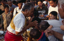 Shaman at ceremony giving blessings by spraying water from his mouth onto devotees headsAsian Cambodian Kampuchea Religion Southeast Asia Kamphuchea Religious