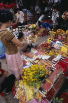 Display of various religious goods for sale in the old market during Chinese New Year with customers buying goodsAsian Cambodian Kampuchea Religion Southeast Asia Kamphuchea