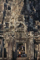 The Bayon.  Tourists framed in doorway of temple complex with relief carving above the lintel.Asian Cambodian Kampuchea Religion Southeast Asia History Holidaymakers Kamphuchea Religious Tourism