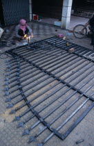 Man welding a metal gate which is lying on the groundAsian Cambodian Kampuchea Southeast Asia Kamphuchea Male Men Guy Male Man Guy