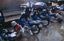 Motorbikes and cars having the local fine red dust washed of themAsian Cambodian Kampuchea Southeast Asia Automobiles Autos Ecology Entorno Environmental Environnement Green Issues Kamphuchea