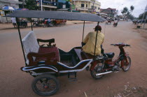 Tuk tuk driver sitting on his motorbike in a quiet dusty streetAsian Cambodian Kampuchea Southeast Asia Kamphuchea