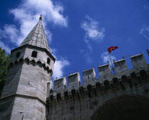 Topkapi Palace. Entrance to grounds looking up at a tower  crenelated wall and Turkish flag flying.