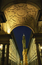 Palazzo Vecchio framed by arch of Loggia Medici and Galleria Uffizi at night.