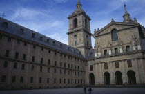 San Lorenzo El Escorial palace and monastery complex built by Felipe II.  Exterior view with tourist visitors standing in square in foreground.