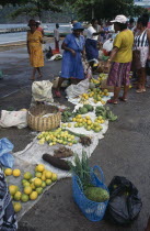 St Lucia, Soufriere, fruit and vegetable vendors and customers at roadside market,  yams, oranges, soursop and limes amongst produce for sale.