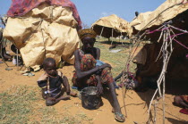 Woman and child sitting outside makeshift shelter in camp for displaced people.refugees  tent  hut  African Children Eastern Africa Female Women Girl Lady Kids Somalian Soomaliya Female Woman Girl La...