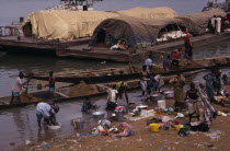 Women washing clothes in river from bank with barges and wooden canoes transporting soil and other goods behind.laundry African Clean Cleaning Female Woman Girl Lady Laundering Nigeran Senegalese Wes...