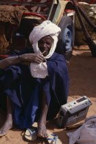 Portrait of Senegalese man seated on ground listening to radio.African Male Men Guy One individual Solo Lone Solitary 1 Male Man Guy Single unitary