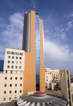 Portomaso Hilton Tower office complex towering above a small church with dome and bell tower