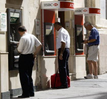 Three men using separate ATM cash machines on Republic Street
