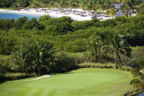 Raffles Resort Trump International Golf Course designed by Jim Fazio. The 8th green and Jambu beach beyond lined with coconut palm trees  palapas and sunbeds