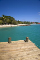 Pigeon Island National Historic Park Tourists on the beach lined with coconut palm trees and a wooden jetty decking in the foreground