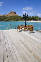 Signal Hill on Pigeon Island National Historic Park seen from a nearby wooden jetty with a table and chairs beside a wrought iron lamppost