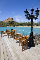 Signal Hill on Pigeon Island National Historic Park seen from a nearby wooden jetty with a table and chairs beside a wrought iron lamppost