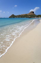 The beach at Sandals Grande St Lucian Spa and Beach Resort hotel with Pigeon Island National Historic Park beyond