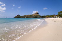 The beach at Sandals Grande St Lucian Spa and Beach Resort hotel with Pigeon Island National Historic Park beyond