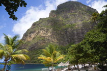 Val des Pitons The white sand beach at the Jalousie Plantation Resort Hotel with the volcanic plug of Petit Piton beyond and tourists on sunbeds beneath palapa sun shades