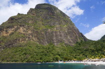 Val des Pitons The white sand beach at the Jalousie Plantation Resort Hotel with the volcanic plug of Petit Piton beyond and tourists on sunbeds beneath palapa sun shades