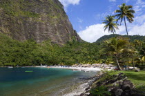Val des Pitons The white sand beach at the Jalousie Plantation Resort Hotel with the volcanic plug of Petit Piton beyond and tourists on sunbeds beneath palapa sun shades