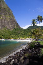 Val des Pitons The white sand beach at the Jalousie Plantation Resort Hotel with the volcanic plug of Petit Piton beyond and tourists on sunbeds beneath palapa sun shades