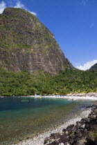 Val des Pitons The white sand beach at the Jalousie Plantation Resort Hotel with the volcanic plug of Petit Piton beyond and tourists on sunbeds beneath palapa sun shades