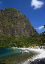 Val des Pitons The white sand beach at the Jalousie Plantation Resort Hotel with the volcanic plug of Petit Piton beyond and tourists on sunbeds beneath palapa sun shades