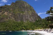 Val des Pitons The white sand beach at the Jalousie Plantation Resort Hotel with the volcanic plug of Petit Piton beyond and tourists on sunbeds beneath palapa sun shades