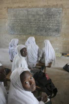 Tanji Village.  African Muslim girls wearing white headscarves attending a class at the Ousman Bun Afan Islamic school.  Girls in foreground looking back towards the camera. TanjehTanjihAfricanIsl...