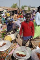 Tanji market.  Young girl selling sweet snacks at Tanji market with older woman seated at stall beside her.TanjihTanjehAfricanraceFemale Women Girl Lady Gambian Immature Kids Old Senior Aged Wes...