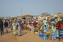 Tanji market.  Busy market scene with line of food stalls and crowds of people in brightly coloured dress. TanjihTanjehAfricancolourcolorColored Gambian Western Africa