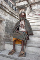 Elderly male Hindu beggar sitting on steps outside the Jagdish Temple wrapped in blanket shawl with painted forehead and grey beard.Culture TraditionSilver CityCasteBelieverBeliefAsia Asian Bha...