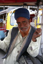 Portrait of auto rickshaw driver inside vehicle with red dyed beard  silver rings and necklace.hennajewelleryjeweleryjobworkingexpressiongesturetransportationtaxituk-tukvehicleAsia Asian B...
