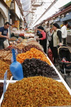 Women with baby in pram making purchase at stall selling dried fruit and nuts including sultanas  apricots and peanuts in covered main food market of Jerusalemdietcookcookingcuisinegroceriesshop...
