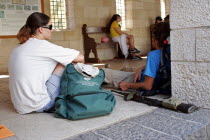 Young Israeli students sitting outside a Christian church with gun lying on ground between them.weaponriflefirearmImmature Isra el Learning Lessons Middle East Religion Religious Christianity Chr...