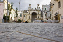 Main square in ancient city of Sassi di Matera or the  Stones of Matera  originating from a prehistoric cave settlement.  UNESCO World Heritage Site.  Cafe bar with outside seating overlooked by churc...